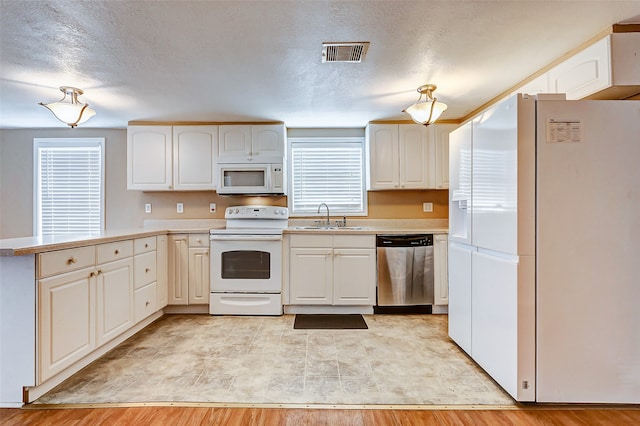 kitchen featuring a wealth of natural light, sink, light wood-type flooring, white appliances, and white cabinetry