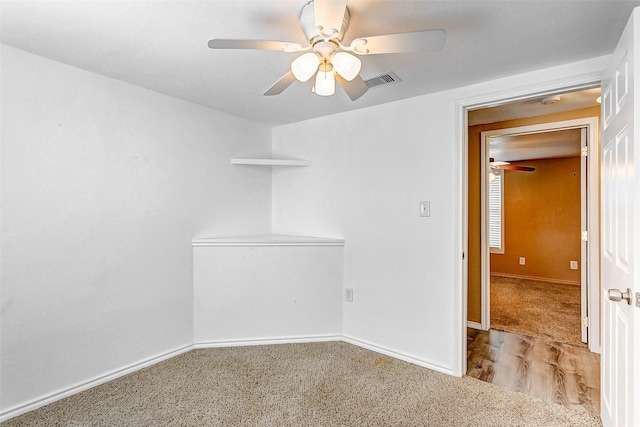 carpeted spare room featuring baseboards, a ceiling fan, and visible vents