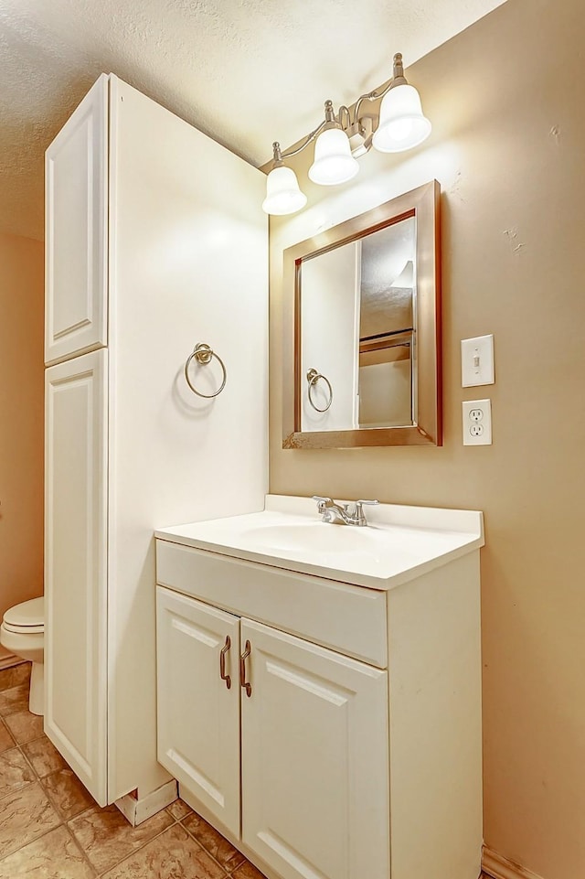bathroom with toilet, vanity, and a textured ceiling