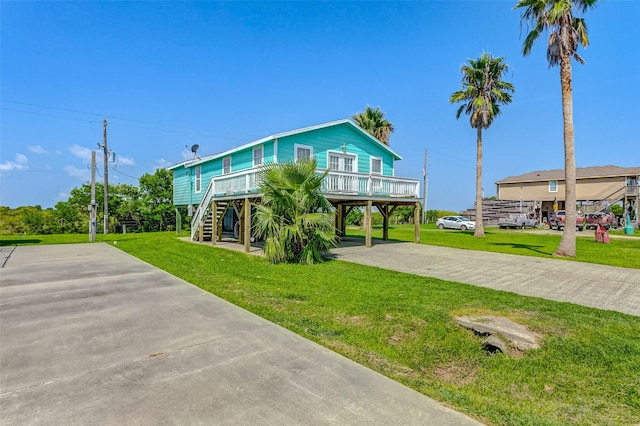 coastal inspired home featuring a carport, a front lawn, stairway, and driveway