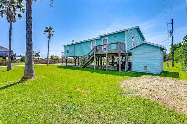 rear view of house featuring stairway, a wooden deck, and a lawn
