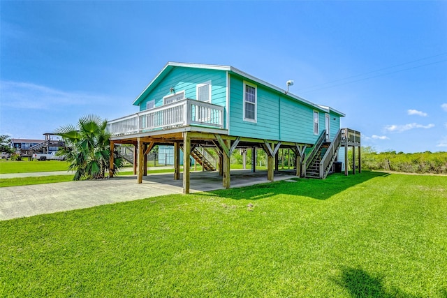 back of property with a carport, a yard, concrete driveway, and stairway