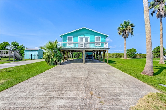 coastal inspired home with a front lawn, a carport, and an outdoor structure