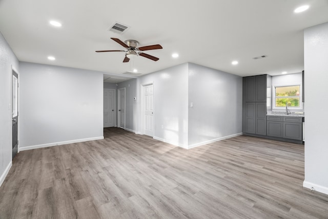 unfurnished living room with ceiling fan, sink, and light hardwood / wood-style flooring