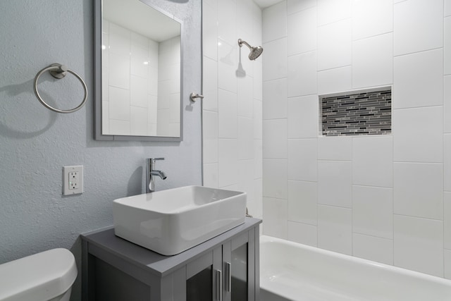 full bathroom featuring tiled shower / bath combo, toilet, and vanity