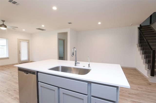 kitchen featuring ceiling fan, light hardwood / wood-style flooring, dishwasher, sink, and a center island with sink