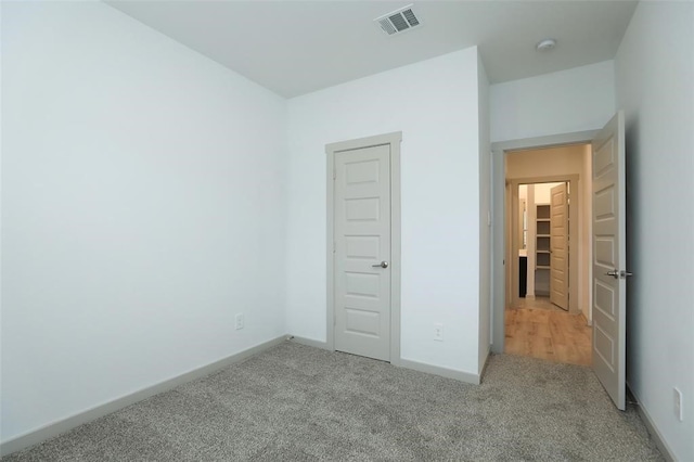 unfurnished bedroom with a closet and light carpet