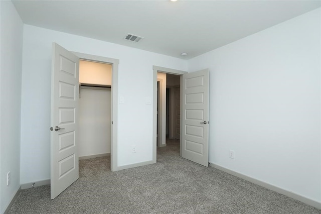 unfurnished bedroom featuring carpet, a closet, and a spacious closet