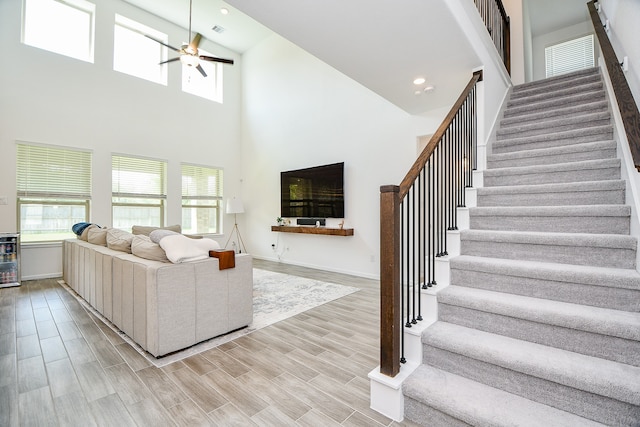 living room featuring ceiling fan, wine cooler, light hardwood / wood-style floors, and a high ceiling