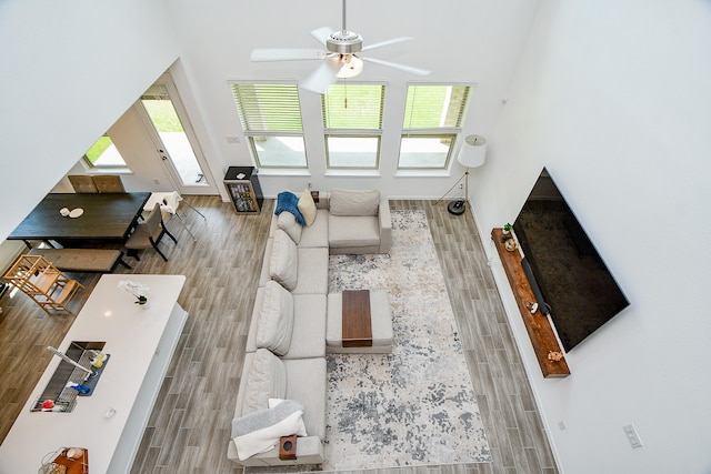 living room with ceiling fan, a towering ceiling, and wood-type flooring