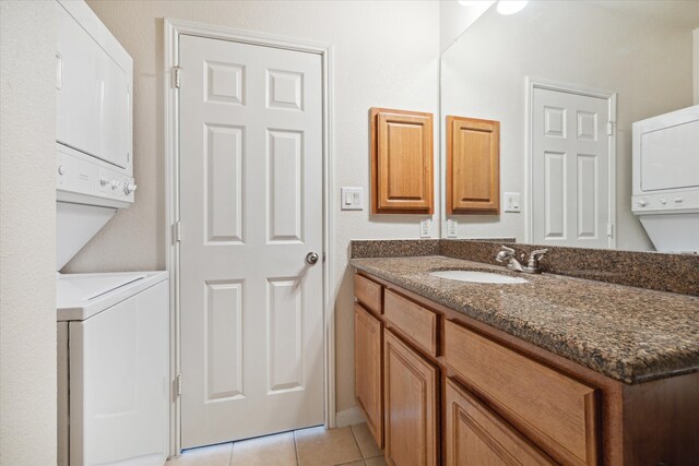 bathroom with stacked washer and clothes dryer, tile patterned floors, and vanity