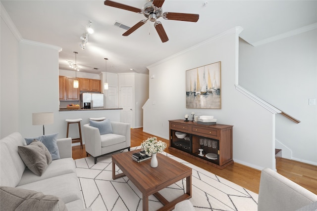 living room with light hardwood / wood-style floors, crown molding, ceiling fan, and track lighting