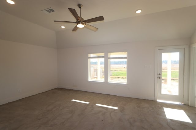 empty room featuring ceiling fan, vaulted ceiling, and carpet