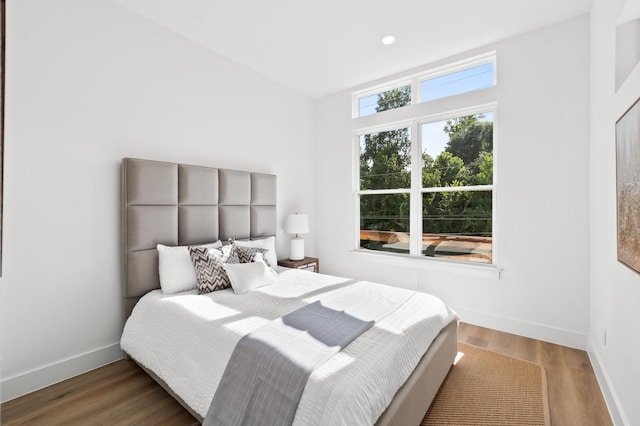 bedroom with baseboards, wood finished floors, and recessed lighting