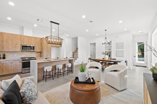 living room featuring stairs, visible vents, a chandelier, and recessed lighting