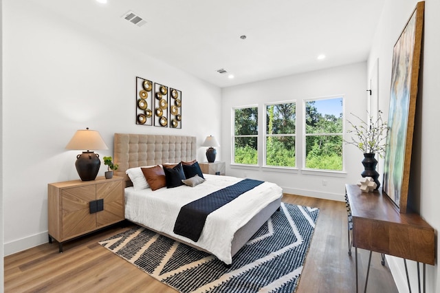 bedroom with baseboards, visible vents, wood finished floors, and recessed lighting