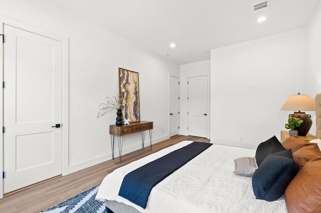 bedroom with baseboards, wood finished floors, visible vents, and recessed lighting