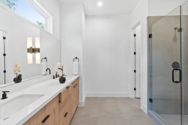 full bath with double vanity, a stall shower, baseboards, and a sink