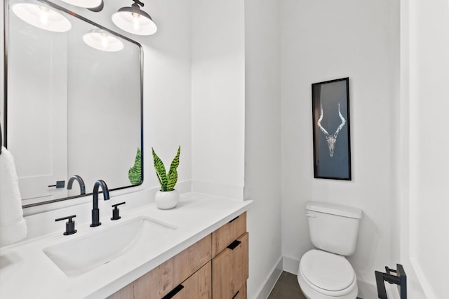 bathroom with toilet, baseboards, and vanity