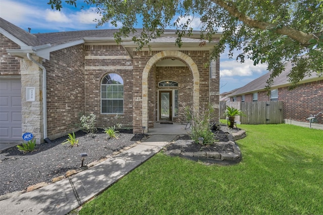 view of front of home with an attached garage, brick siding, a front yard, and fence