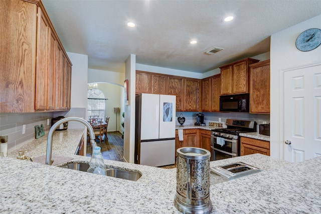 kitchen with double oven range, white fridge, a textured ceiling, sink, and hardwood / wood-style flooring