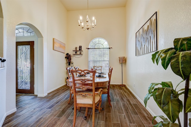 dining space featuring wood tiled floor, arched walkways, a chandelier, and baseboards