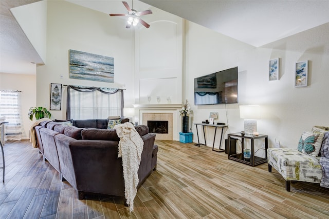 living room with high vaulted ceiling, light wood-type flooring, ceiling fan, and a fireplace