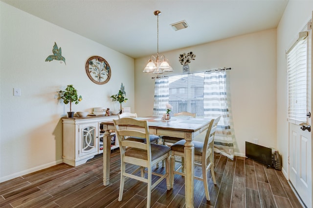 dining room with baseboards, wood finish floors, visible vents, and a notable chandelier