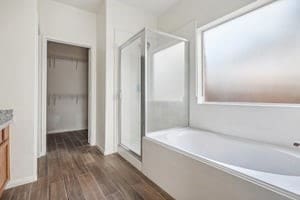 bathroom with a walk in closet, a shower stall, vanity, wood finished floors, and a bath