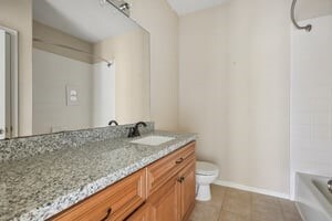 bathroom featuring tile patterned flooring, toilet, vanity, bathing tub / shower combination, and baseboards