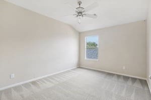 empty room with light carpet, ceiling fan, and vaulted ceiling