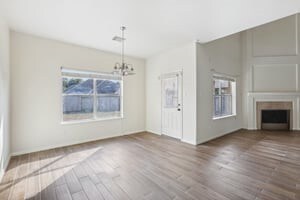 unfurnished dining area with a notable chandelier, a fireplace, and wood finished floors