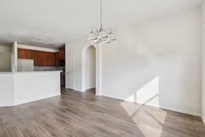 unfurnished living room with a notable chandelier, arched walkways, and wood finished floors