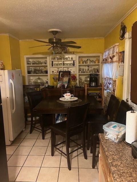 5211 Pensdale, Houston, TX 77033 - dining room featuring light tile patterned floors, ornamental molding, a textured ceiling, and a ceiling fan