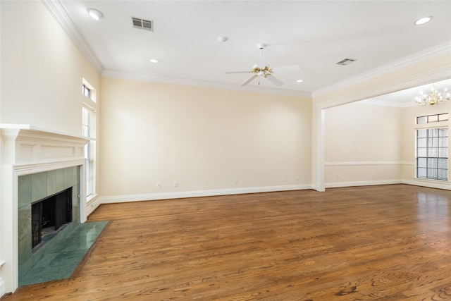 unfurnished living room with ceiling fan with notable chandelier, a wealth of natural light, wood-type flooring, and a fireplace