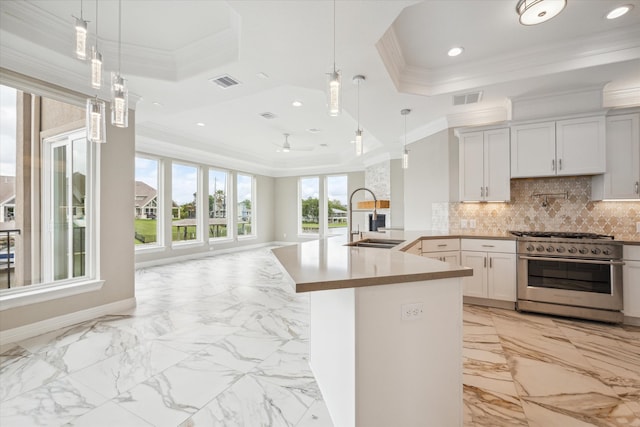 kitchen with backsplash, a tray ceiling, light tile patterned floors, sink, and high end stove