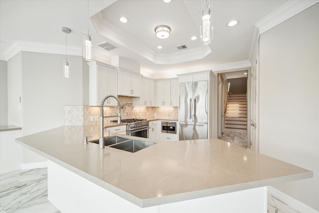 kitchen featuring pendant lighting, a tray ceiling, kitchen peninsula, crown molding, and high quality appliances