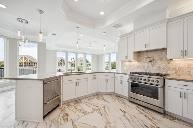 kitchen featuring high end stainless steel range oven, a tray ceiling, light tile patterned floors, sink, and decorative light fixtures