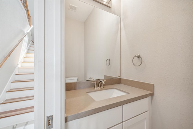 bathroom with visible vents, a textured wall, and vanity