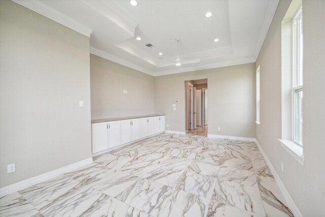 tiled spare room with ceiling fan, a tray ceiling, and ornamental molding