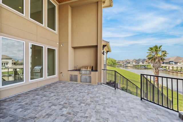 view of patio with area for grilling, a grill, and a water view