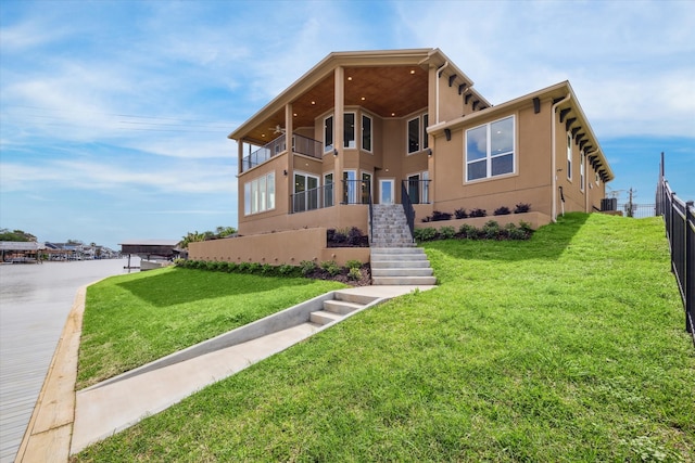 view of front of house with a balcony, central AC unit, and a front lawn