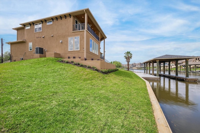 view of home's exterior with stucco siding, a water view, a lawn, a boat dock, and a balcony