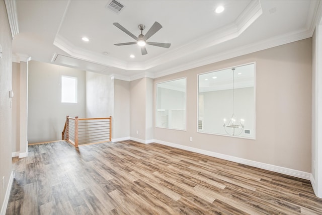 empty room featuring ceiling fan with notable chandelier, crown molding, a tray ceiling, and light hardwood / wood-style floors