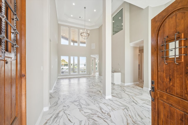 tiled entrance foyer featuring a notable chandelier, a high ceiling, and ornamental molding