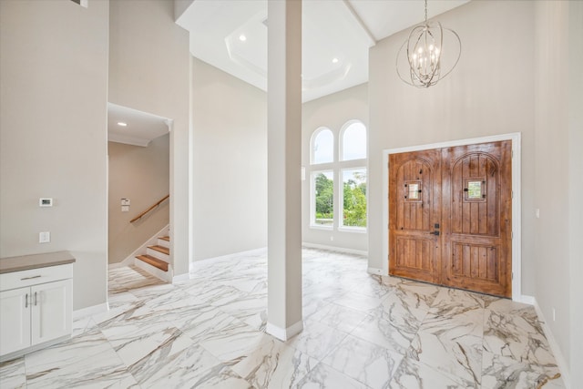 foyer entrance with an inviting chandelier, a tray ceiling, a high ceiling, and light tile patterned floors