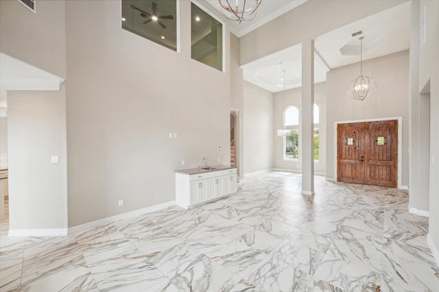 foyer entrance with a notable chandelier, light tile patterned flooring, and a high ceiling