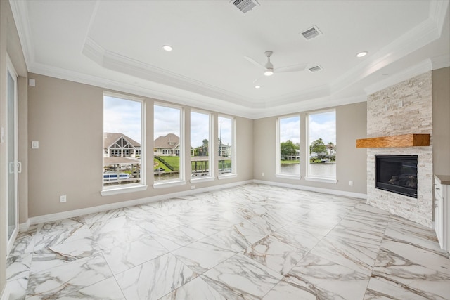 unfurnished living room with a wealth of natural light, a fireplace, a tray ceiling, and light tile patterned flooring