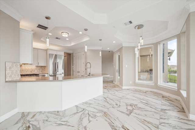 kitchen with visible vents, stainless steel refrigerator, a tray ceiling, crown molding, and a sink