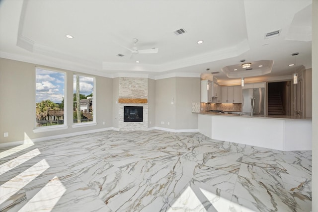 502 Amalfi Dr, Kemah, TX 77565 - unfurnished living room featuring a tray ceiling, recessed lighting, ornamental molding, a ceiling fan, and light marble finish flooring